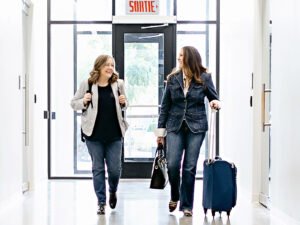 Heidi Thompson and Marietta Stalcup Walking down a hall with luggage